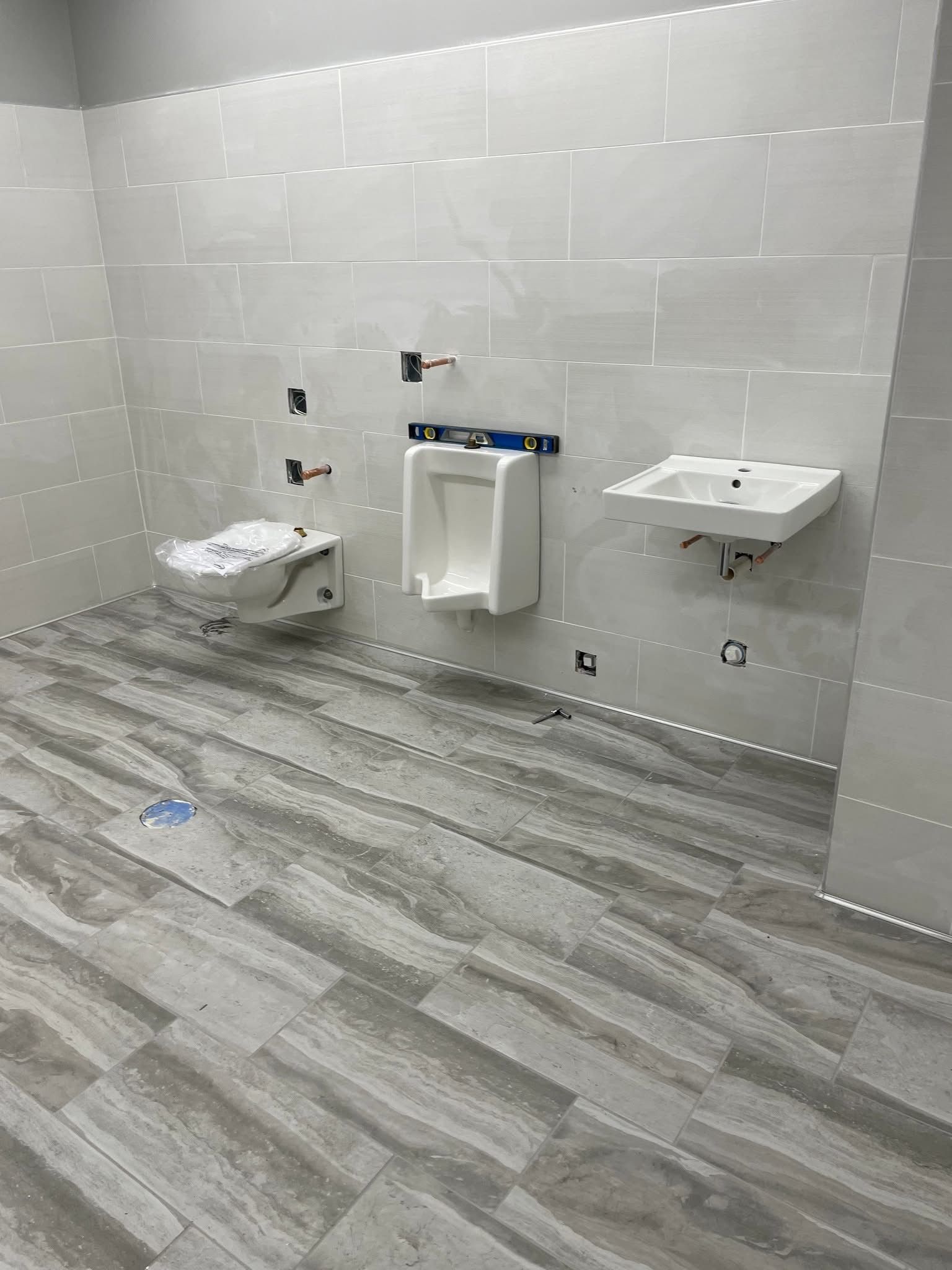 bathroom under construction with a toilet, urinal, and sink