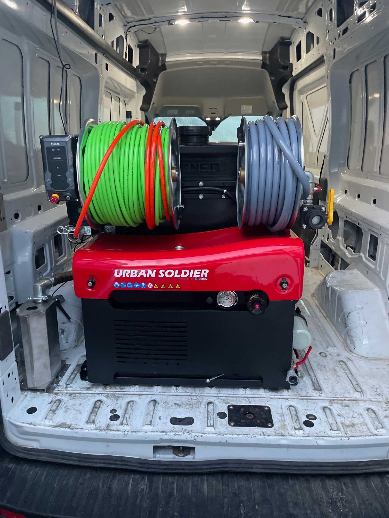 red and black generator with hose reels in a white van