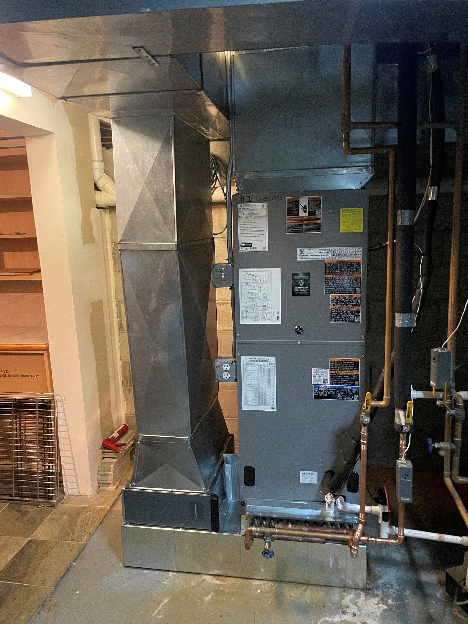 Basement HVAC area with gray furnace, ductwork, and exposed pipes against unfinished walls.