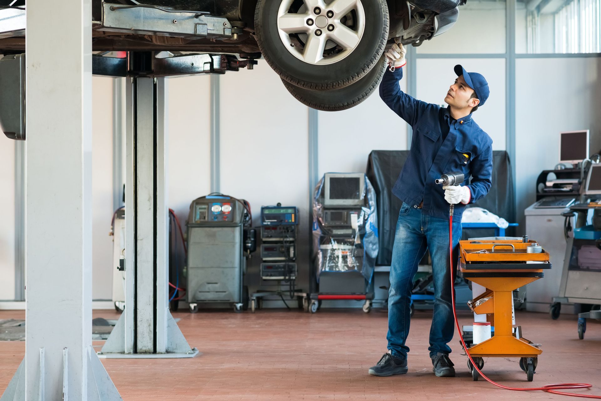 Mechanic inspecting vehicle raised on a lift in a repair shop.