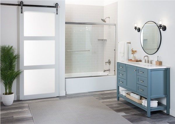 Bright accessible bathroom with walk-in shower, grab bars, and white tub beside pedestal sink