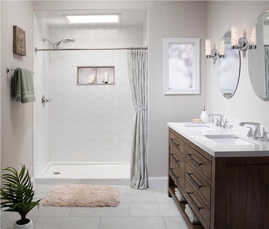 Bright accessible bathroom with walk-in shower, grab bars, and white tub beside pedestal sink