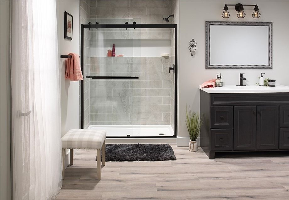 Modern bathroom with a glass shower, vanity, mirror, bench, and neutral tile flooring.