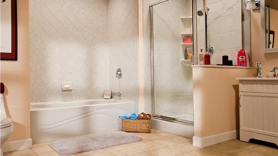 Bright bathroom with a bathtub, glass shower, wicker basket, and beige tile flooring.