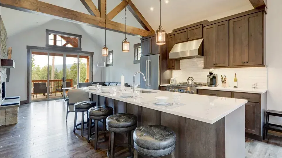 Modern kitchen with large island, pendant lights, gray cabinetry, and wood-beam ceiling