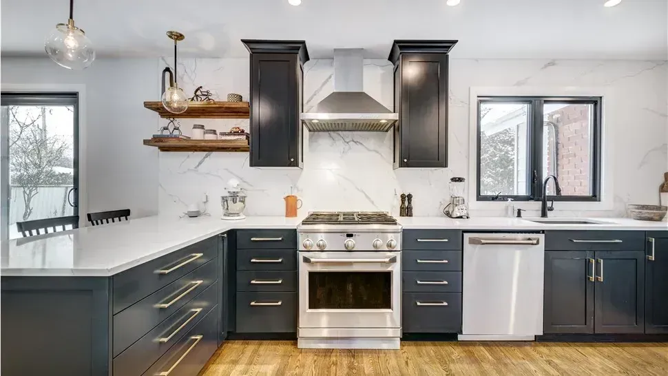Modern kitchen with dark cabinets, white countertops, stainless stove, and bright windows