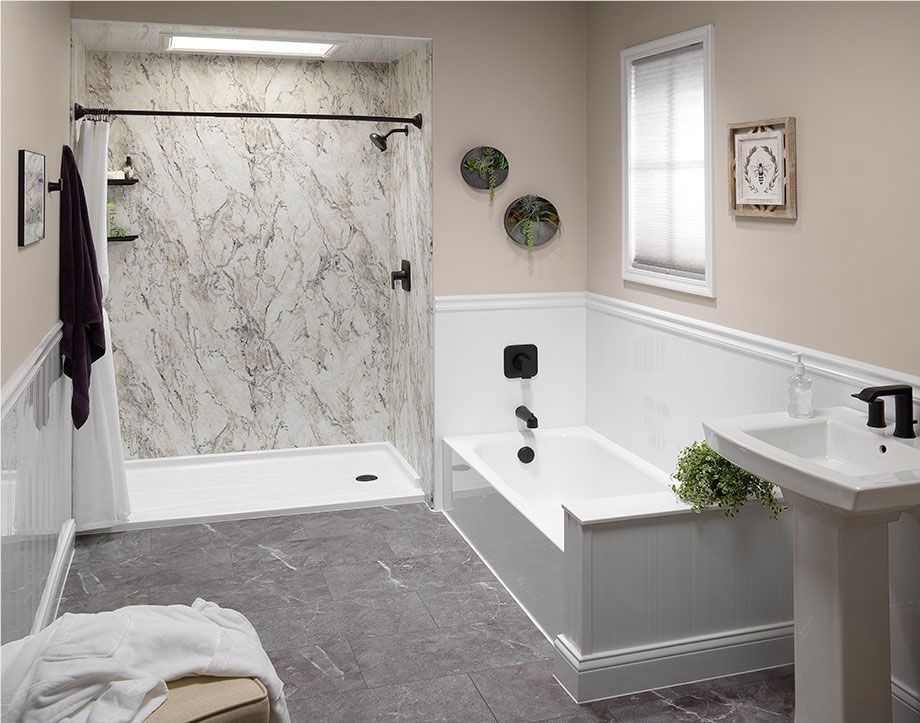 Accessible bathroom with walk-in shower, grab bars, bathtub, and white sink on gray carpet.