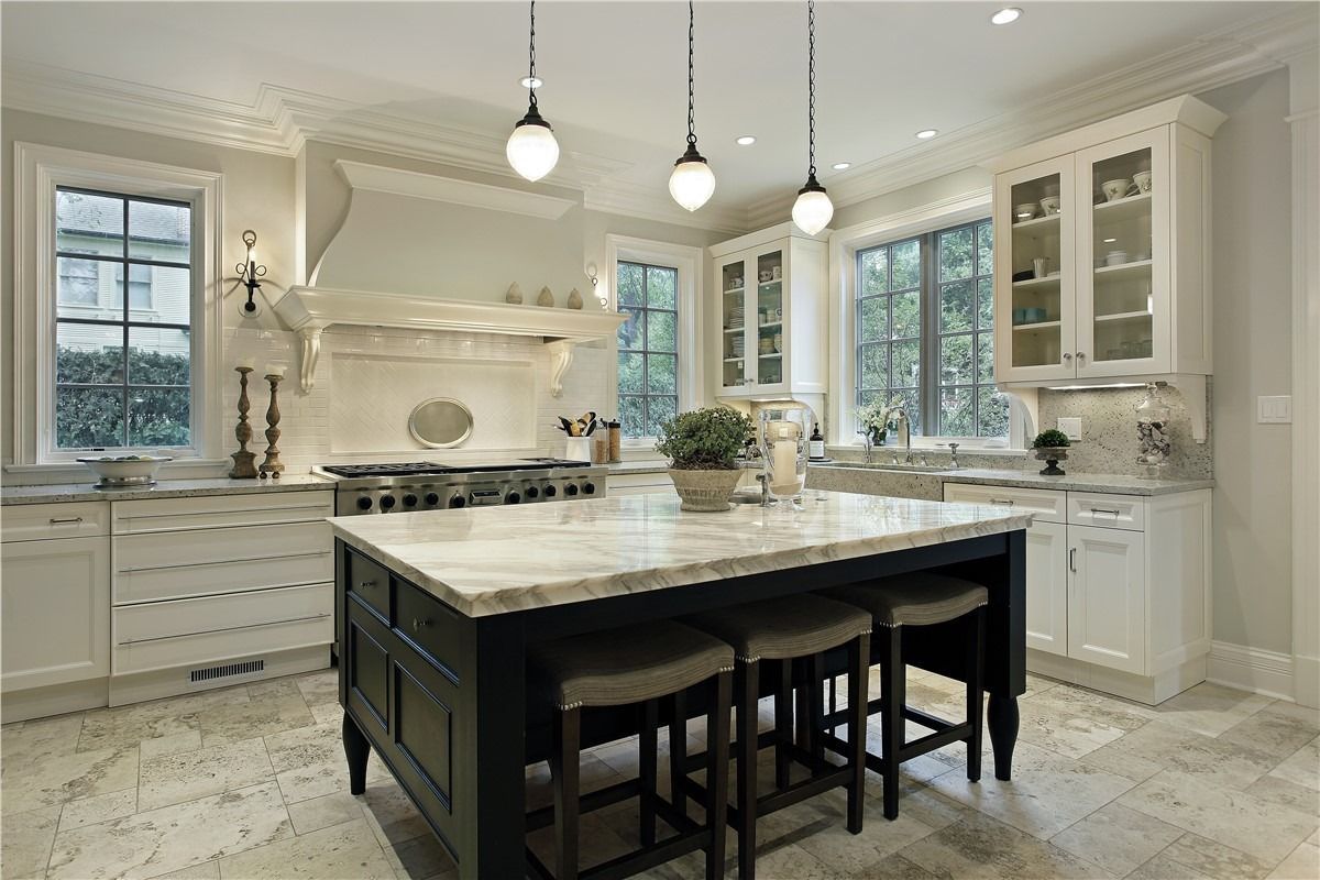 Bright white kitchen with marble island, pendant lights, and large windows