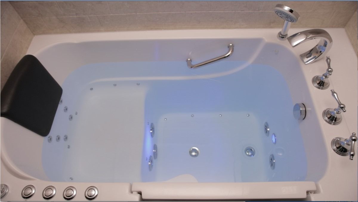White bathtub with built-in jets, chrome fixtures, and a black headrest in a bathroom.