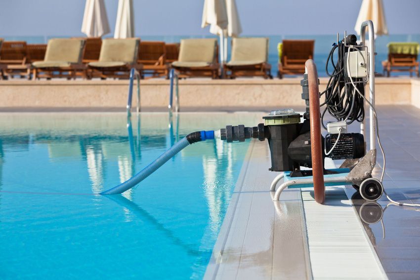 A vacuum cleaner is attached to the side of a swimming pool.