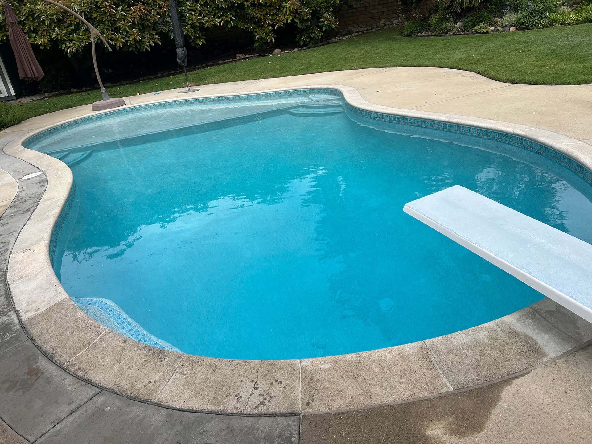 A large swimming pool with a diving board in the middle of it.