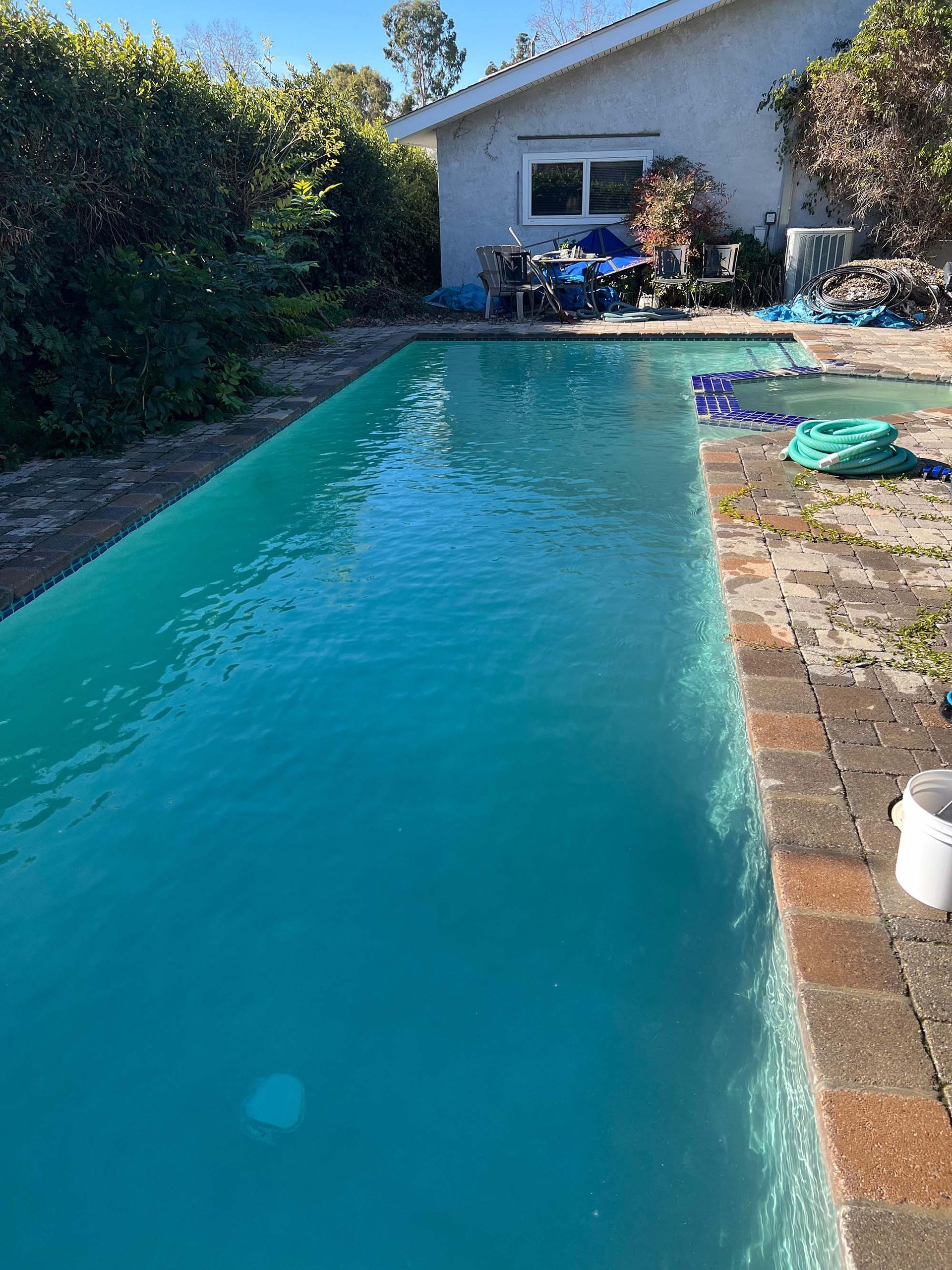 There is a large swimming pool in front of a house.