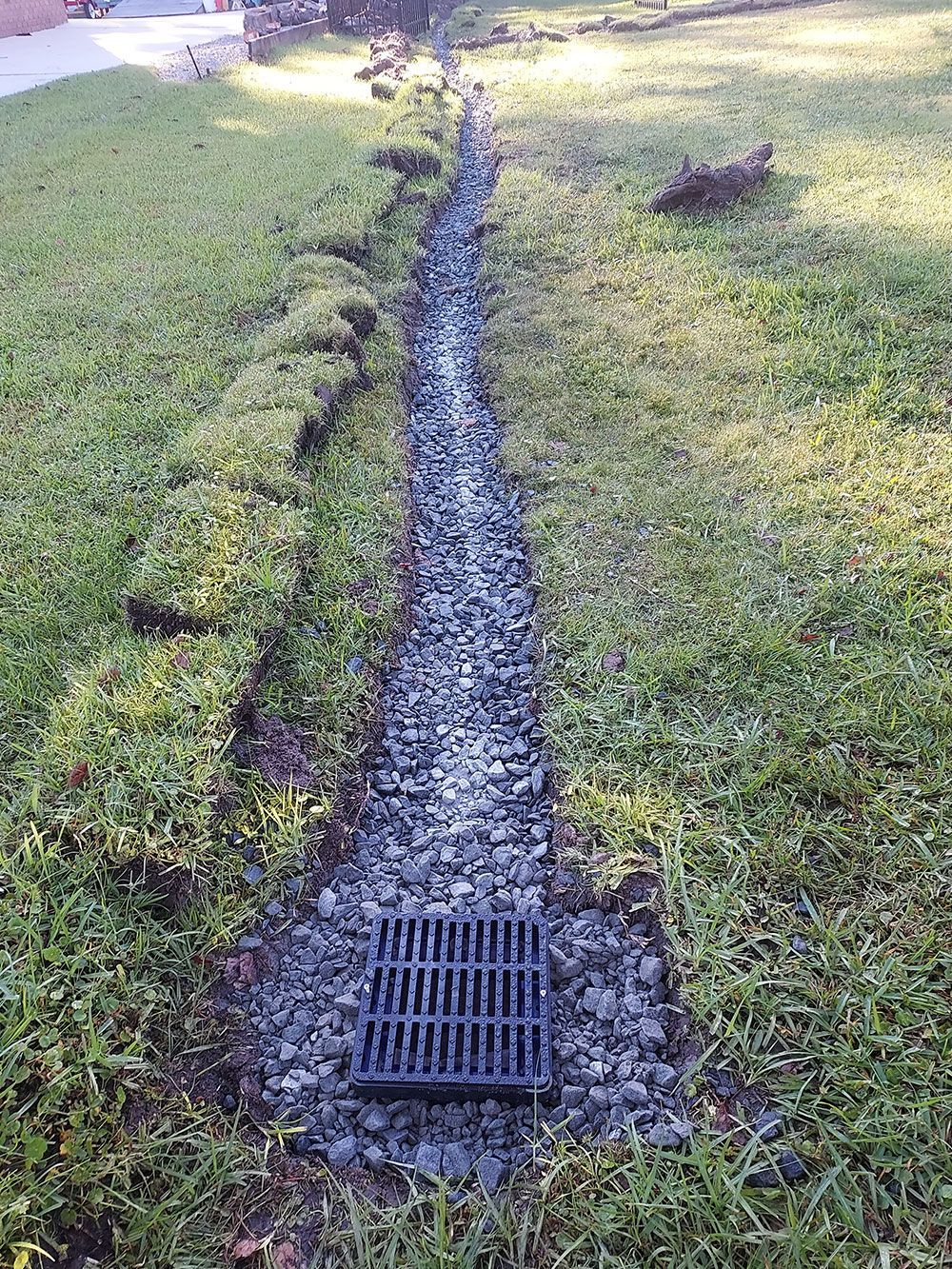 A drain is sitting in the middle of a lush green field.