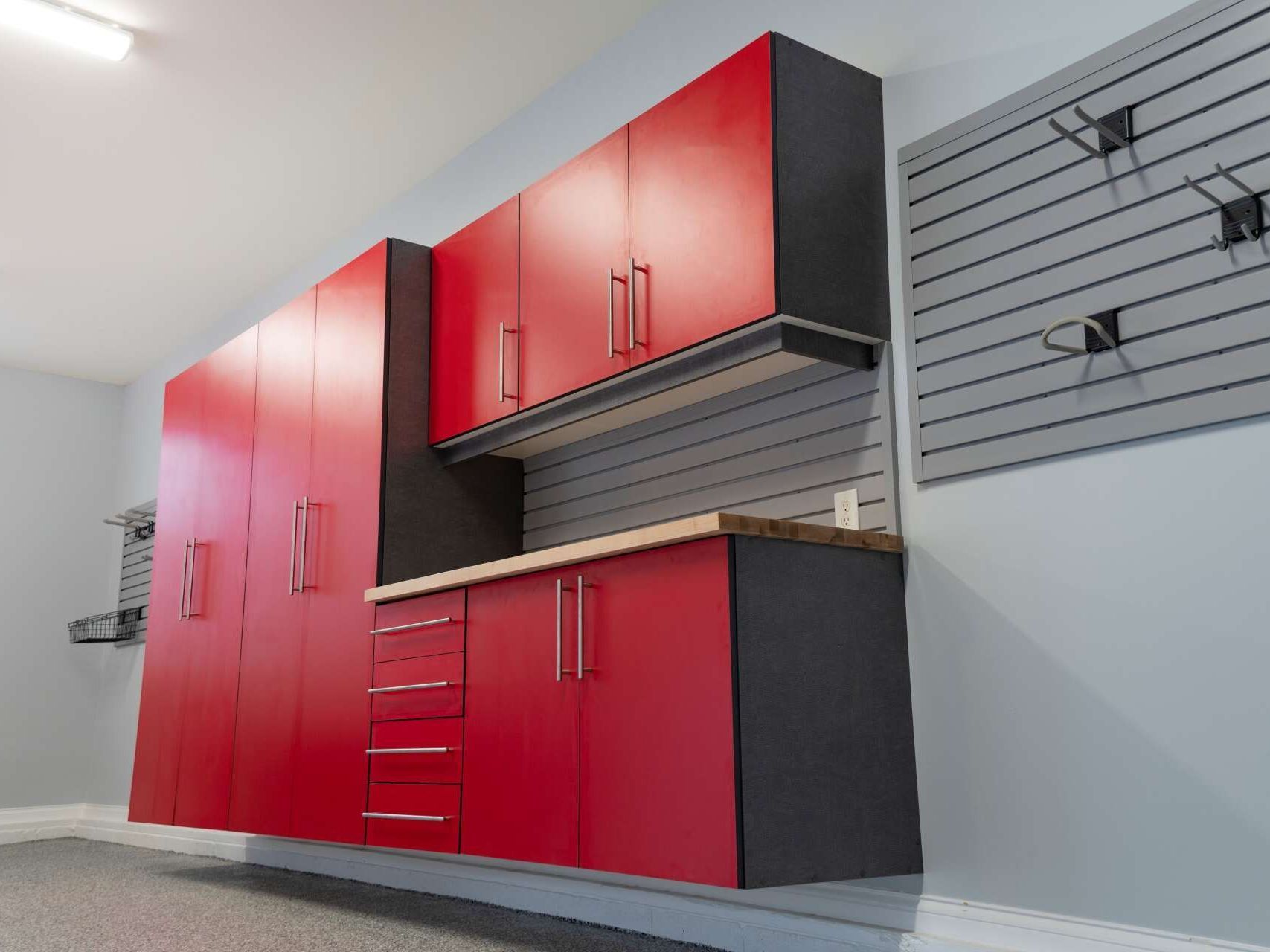 A garage with red cabinets and a gray wall.