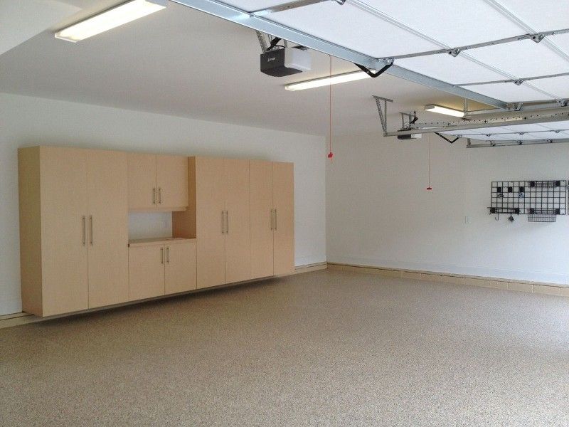 An empty garage with lots of cabinets and a garage door open