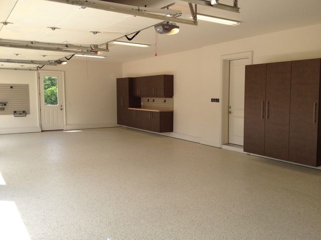 An empty garage with brown cabinets and a garage door open