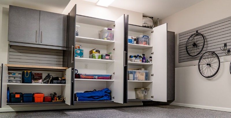 A garage with lots of shelves and cabinets and a bike hanging on the wall.