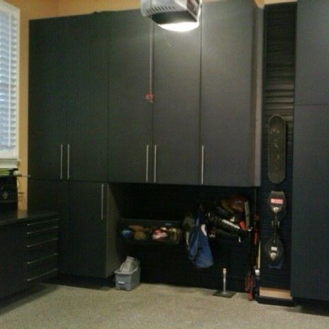 A garage with black cabinets and a skateboard hanging on the wall