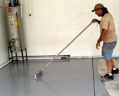A man is using a broom to clean a garage floor