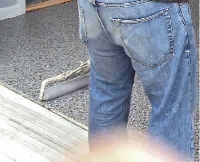 A person wearing blue jeans is standing on a wooden floor.