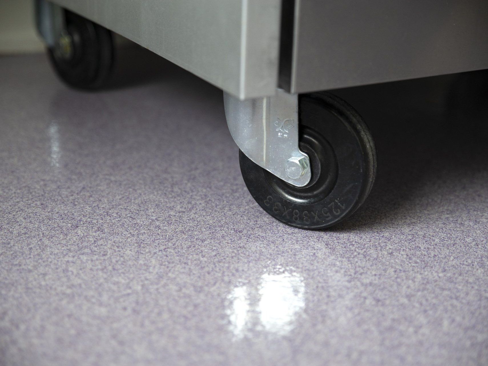 A close up of a refrigerator with wheels on a purple floor.