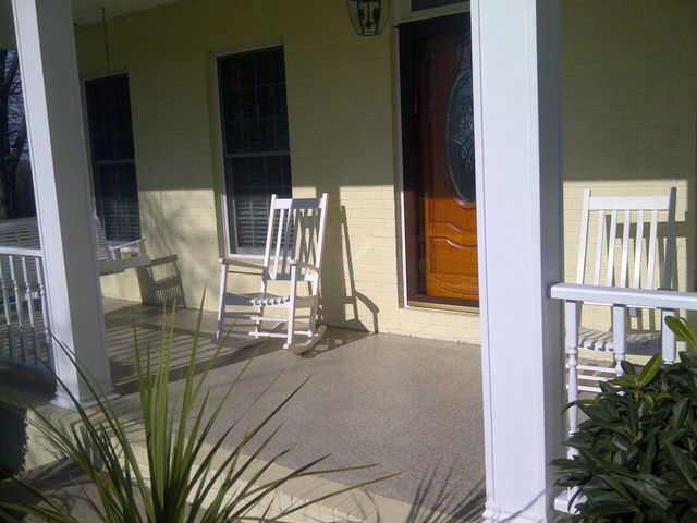 A porch with two white rocking chairs on it