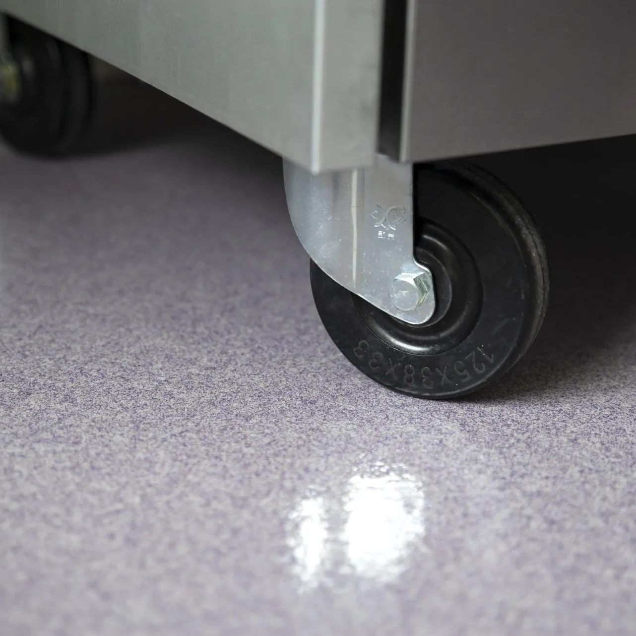 A close up of a refrigerator with wheels on a purple floor.