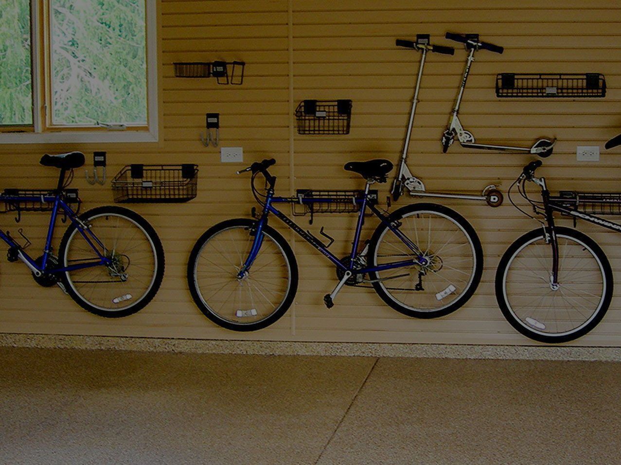 A row of bicycles are hanging on a wall in a garage.