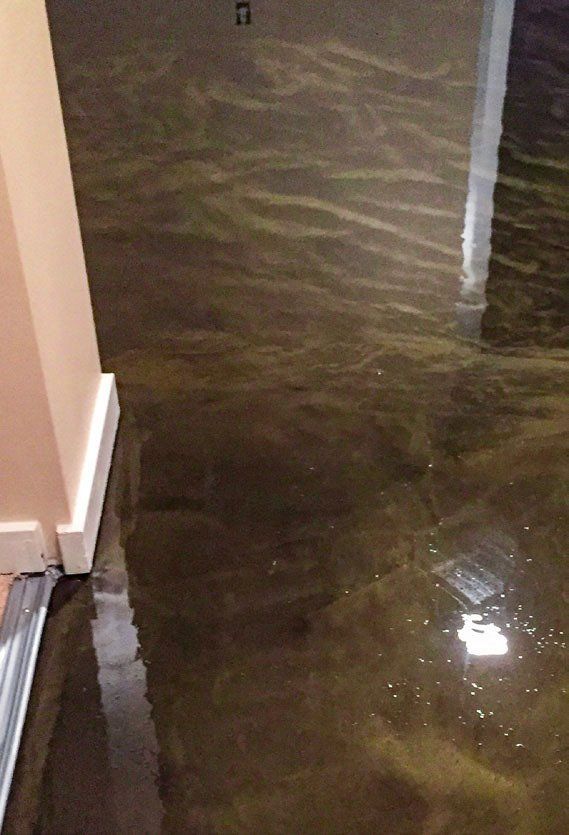 A room with a flooded floor and a reflection of a light on the floor.