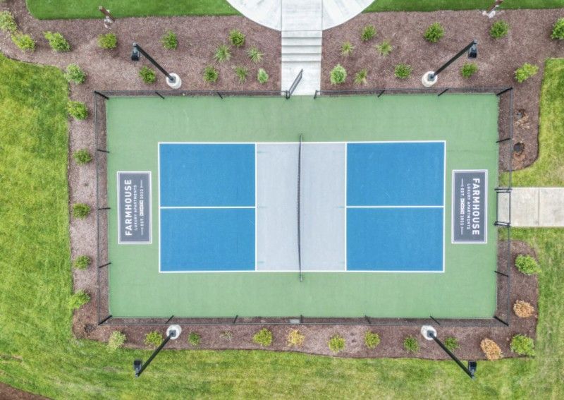 An aerial view of a tennis court surrounded by grass and trees.