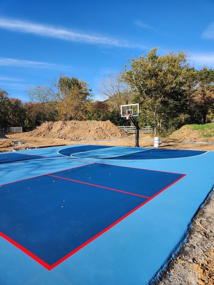 A blue and red basketball court with a basketball hoop in the background.