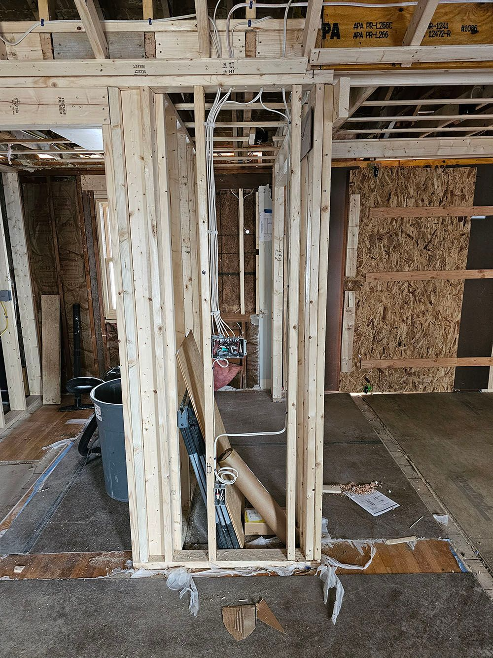 Interior construction framing with exposed wood studs, a bucket, and a partially built wall.