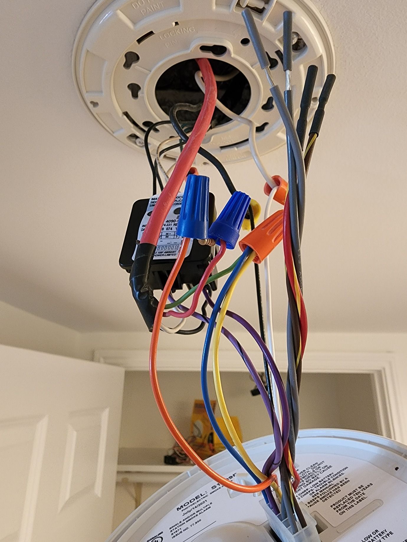 Ceiling light fixture with exposed multicolored electrical wires hanging loose in a doorway