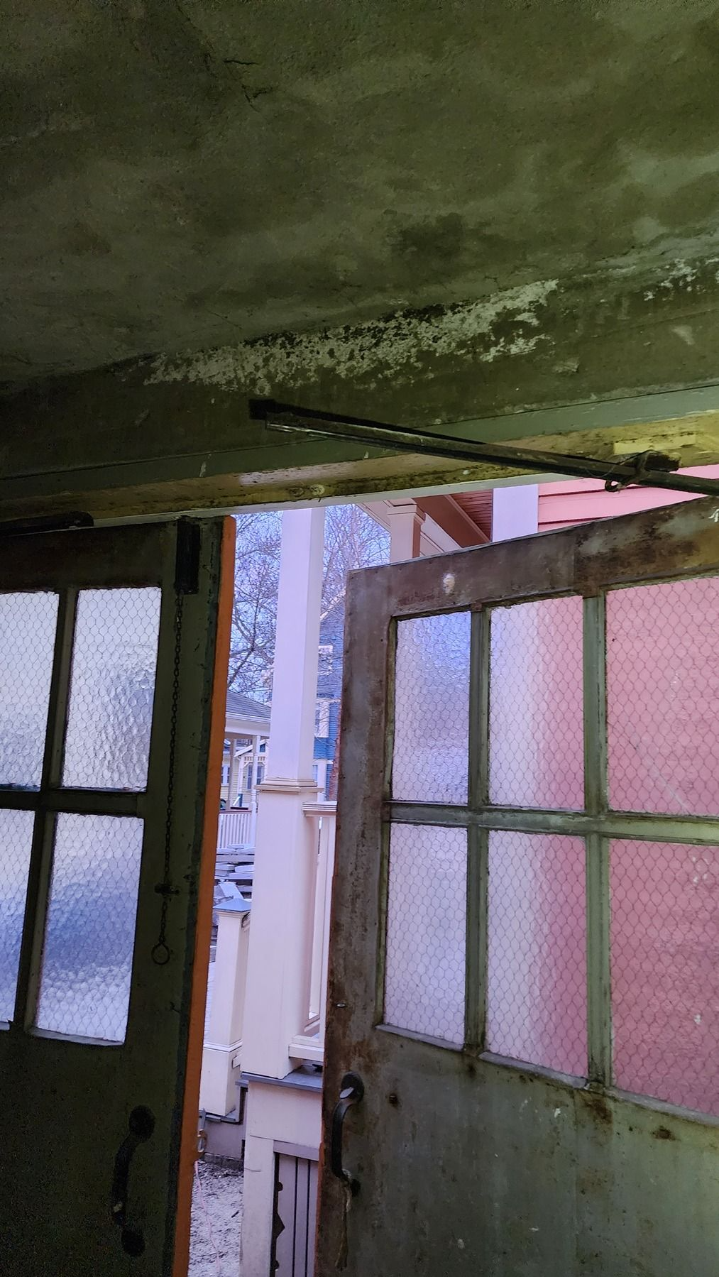 Open doorway in a dim room, with frosted glass panels and a view outside.