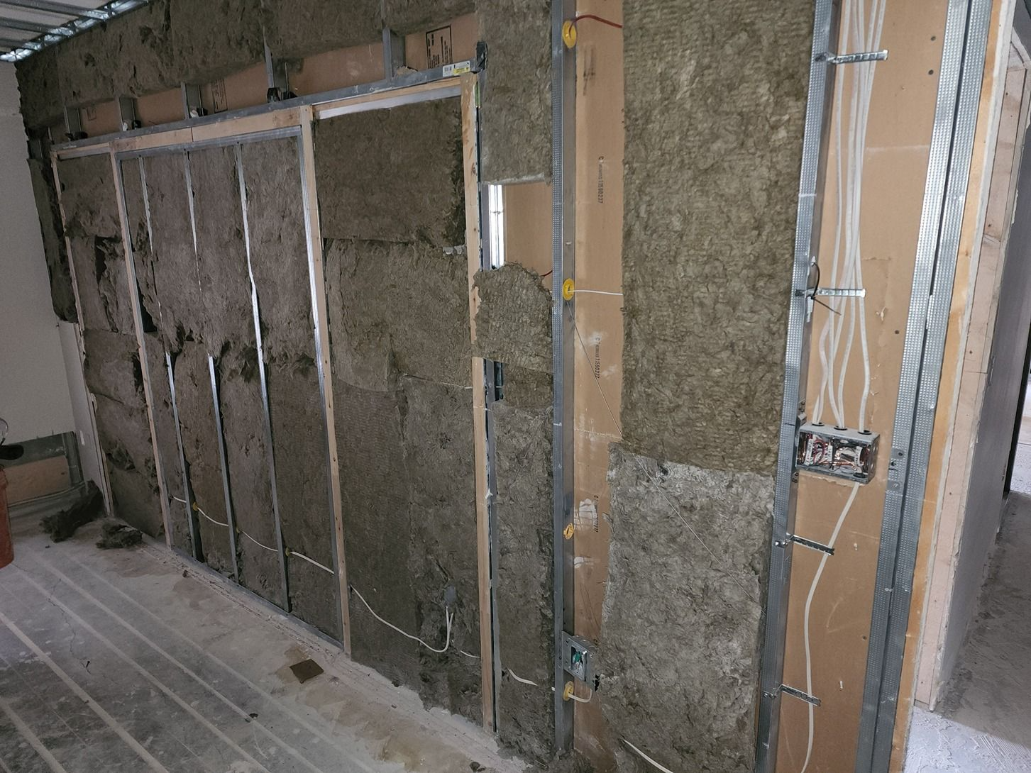 Wall framing with exposed insulation and electrical wiring inside an unfinished room