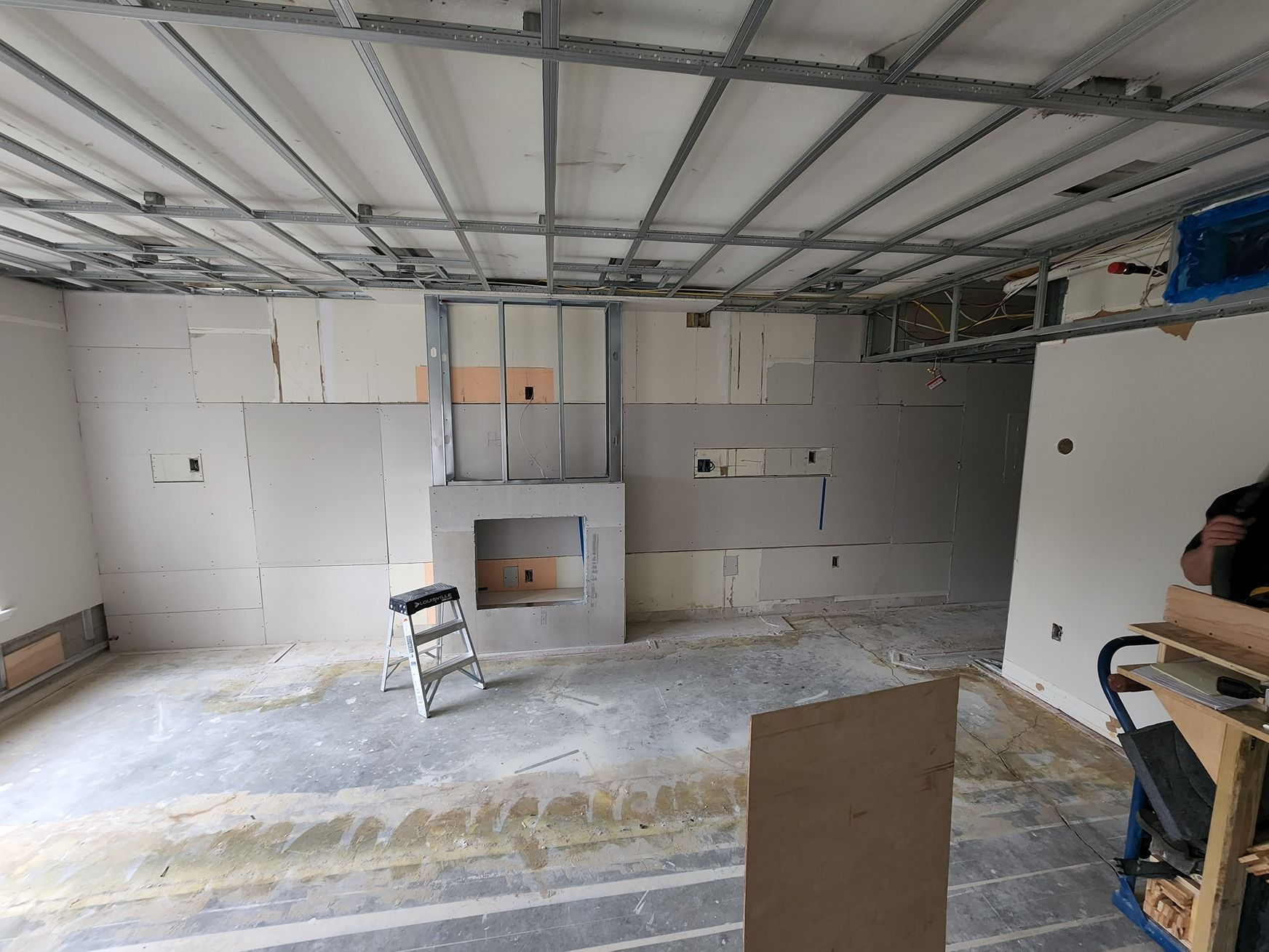 Empty room under construction with exposed ceiling, gray walls, and a small chair in the center