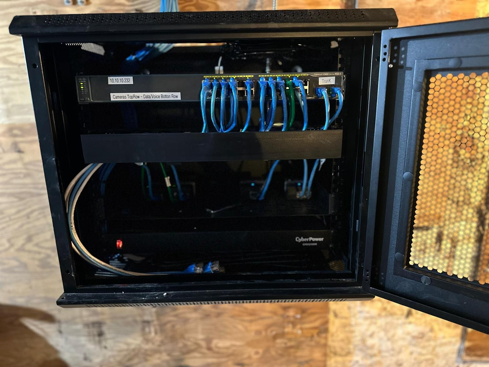 Open network cabinet with patch cables and switches inside, door open on the right.