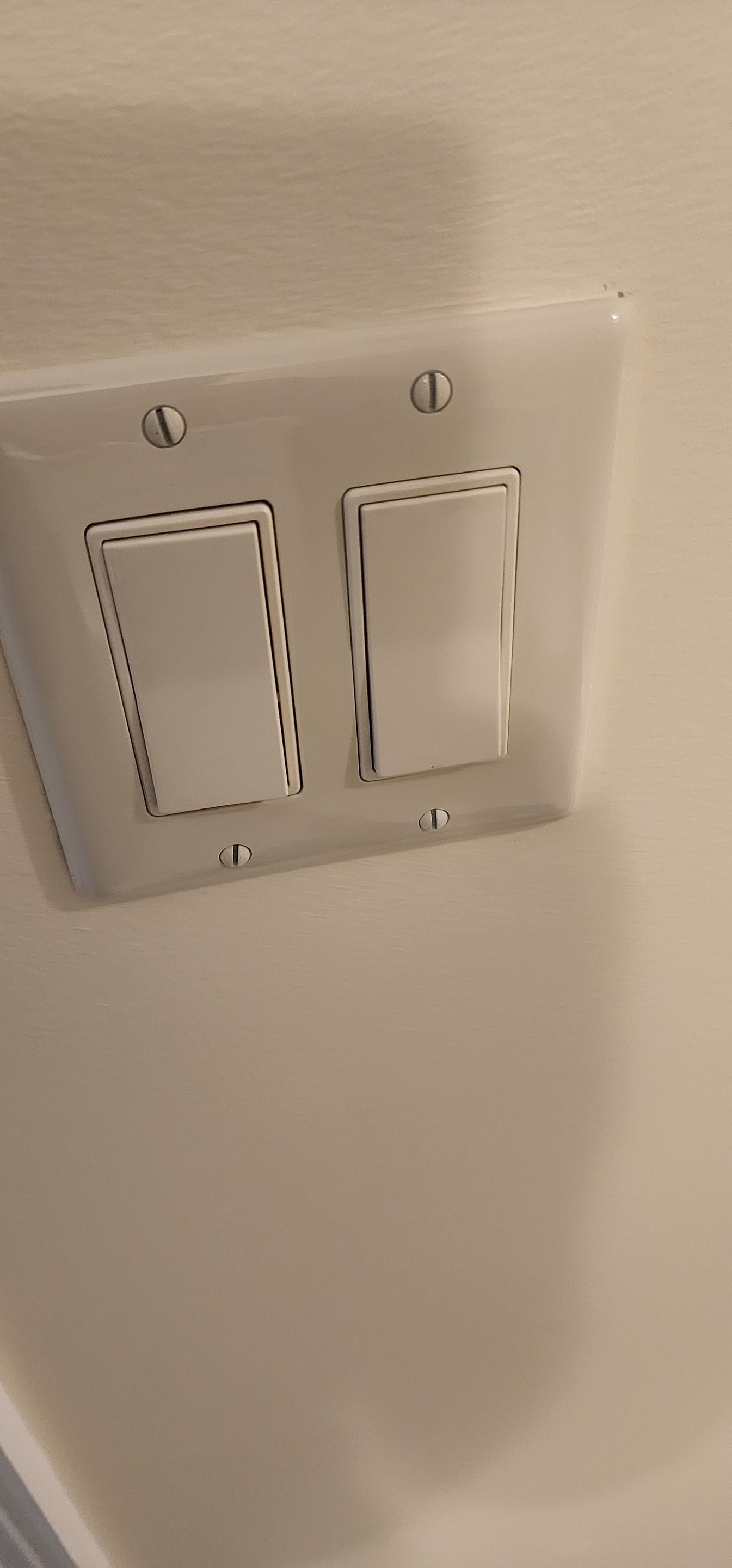Two white wall switches on a beige wall, one switch with a black dotted outline around it