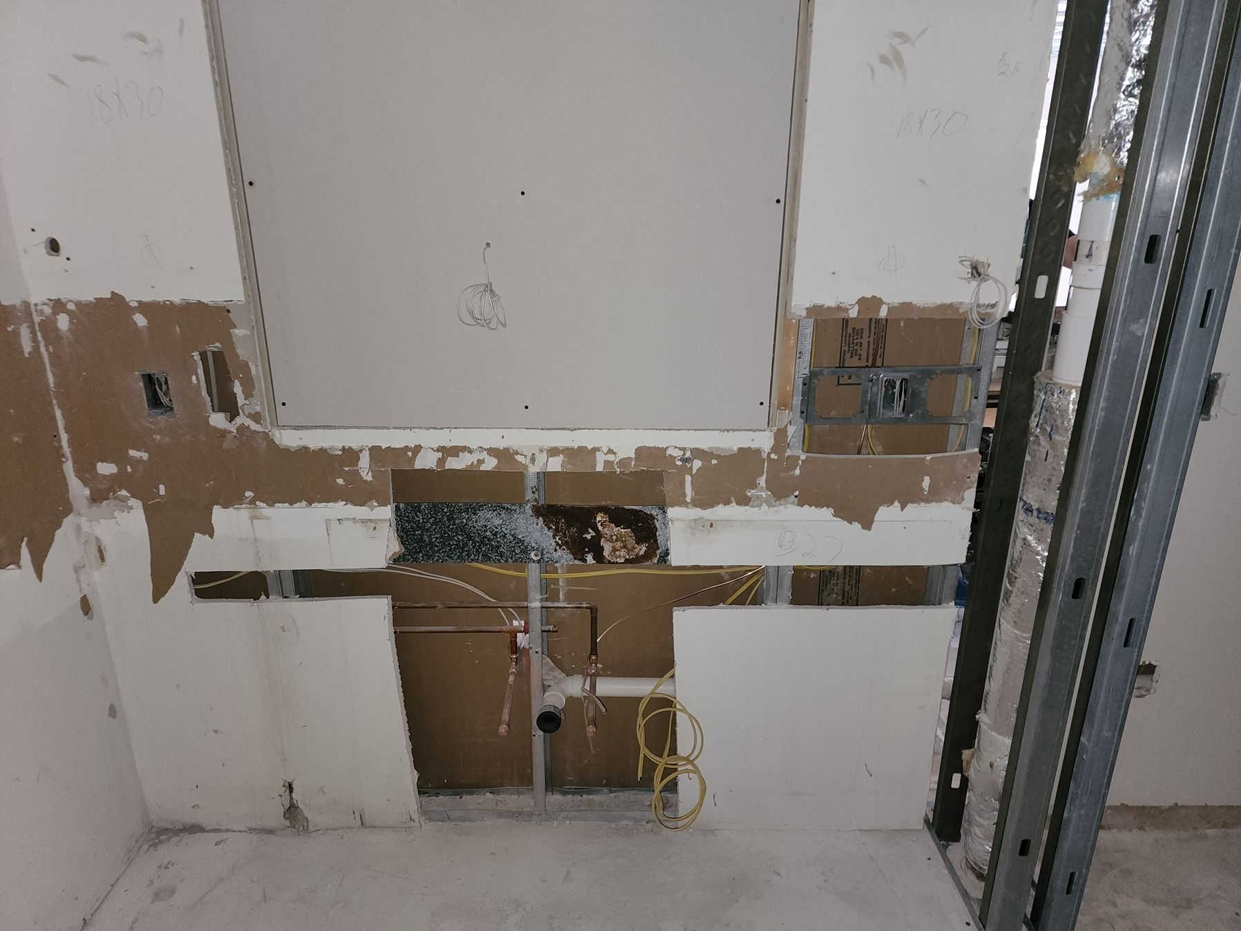 Partially stripped interior wall with exposed pipes and wiring during renovation