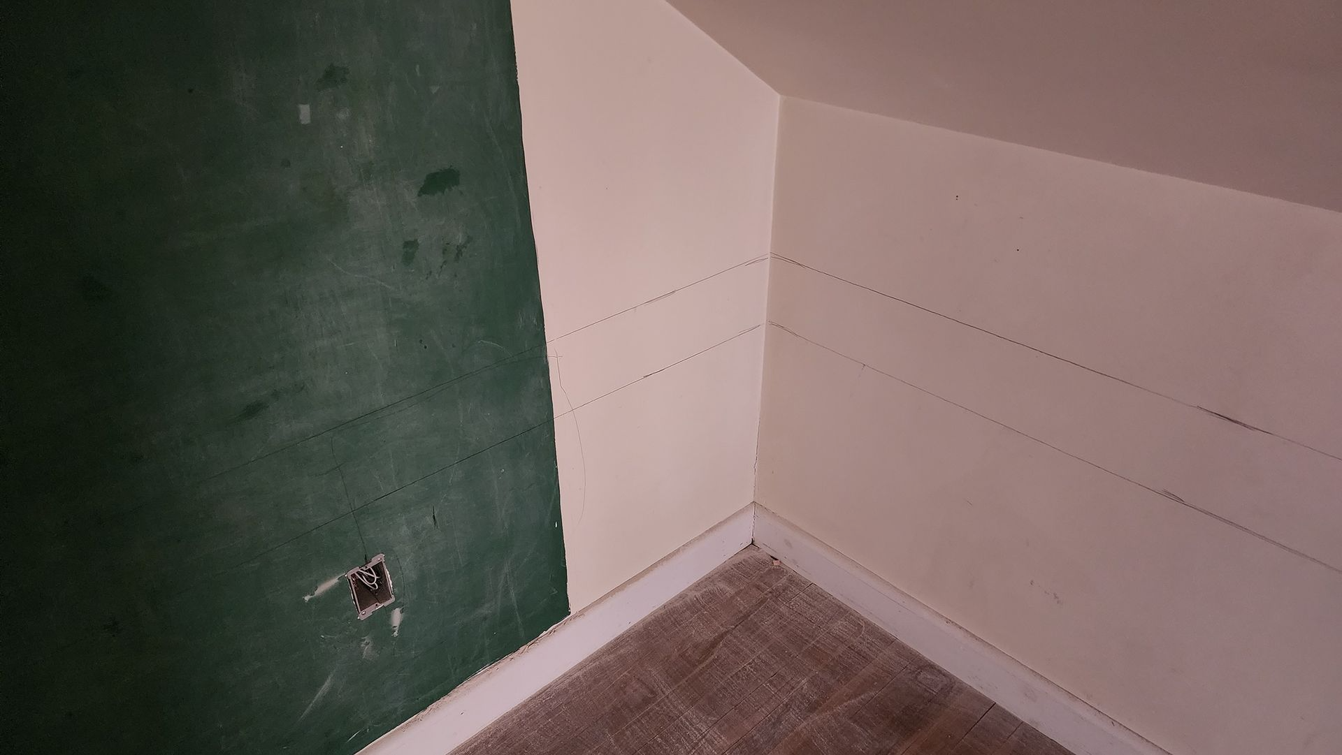 Empty corner of a room with a green wall, white walls, and carpeted floor.