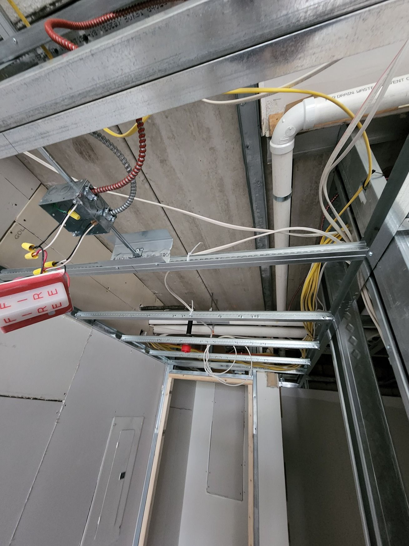 Ceiling utility area with metal framing, cables, and pipes above a doorway.