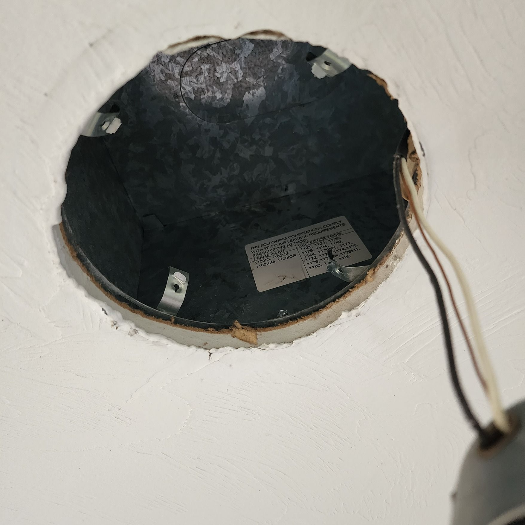 Open ceiling light fixture with exposed black interior and hanging white-black wires