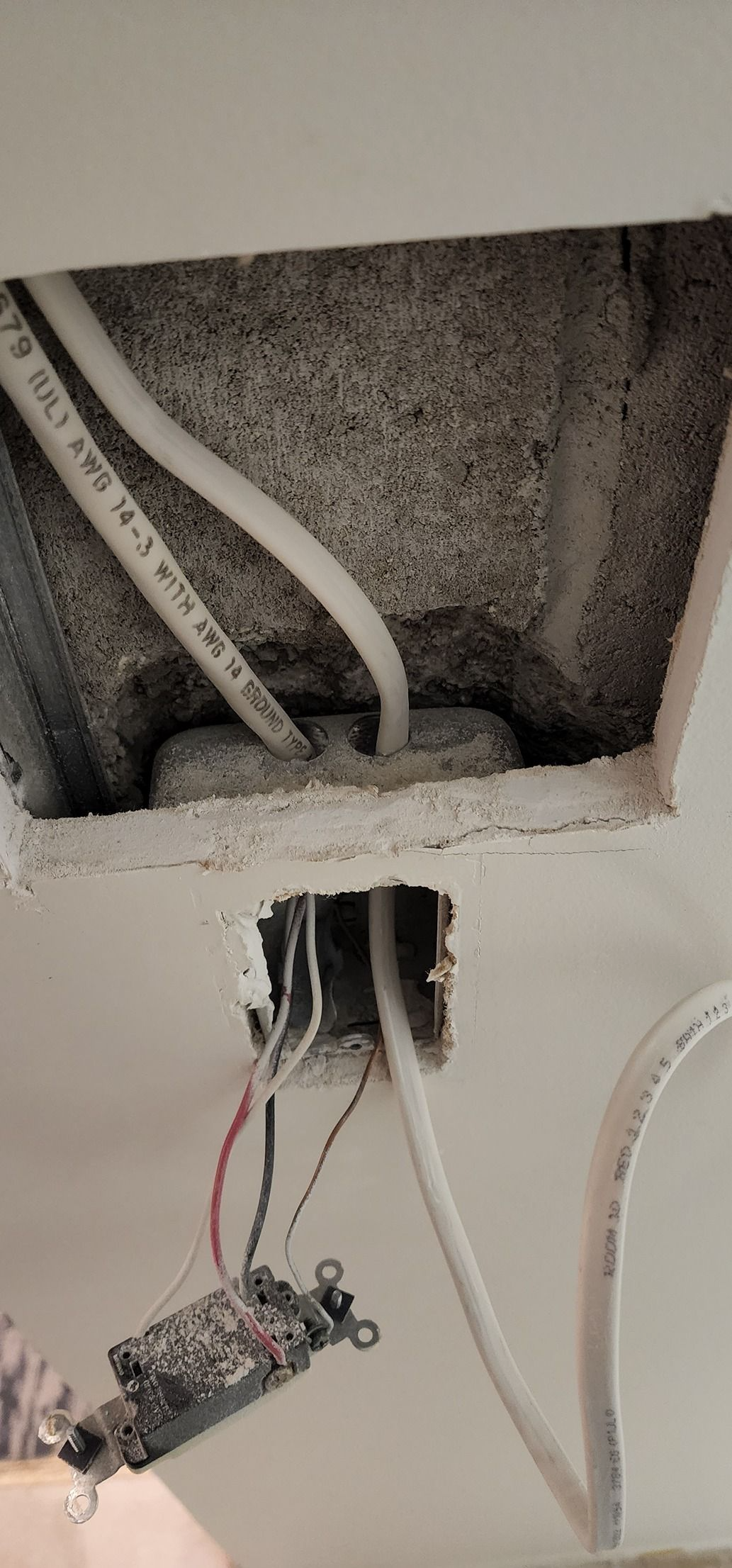 Open wall electrical box with exposed wires and a hanging outlet plate in a rough cutout.