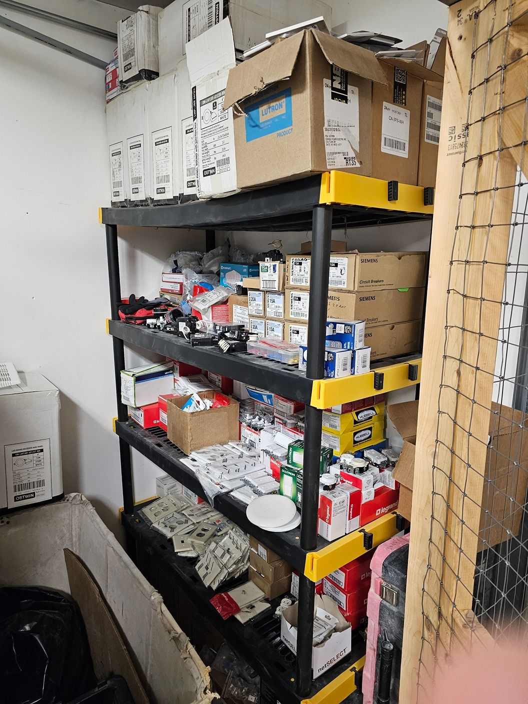 Storage shelves filled with assorted boxes, tools, and supplies in a cluttered room