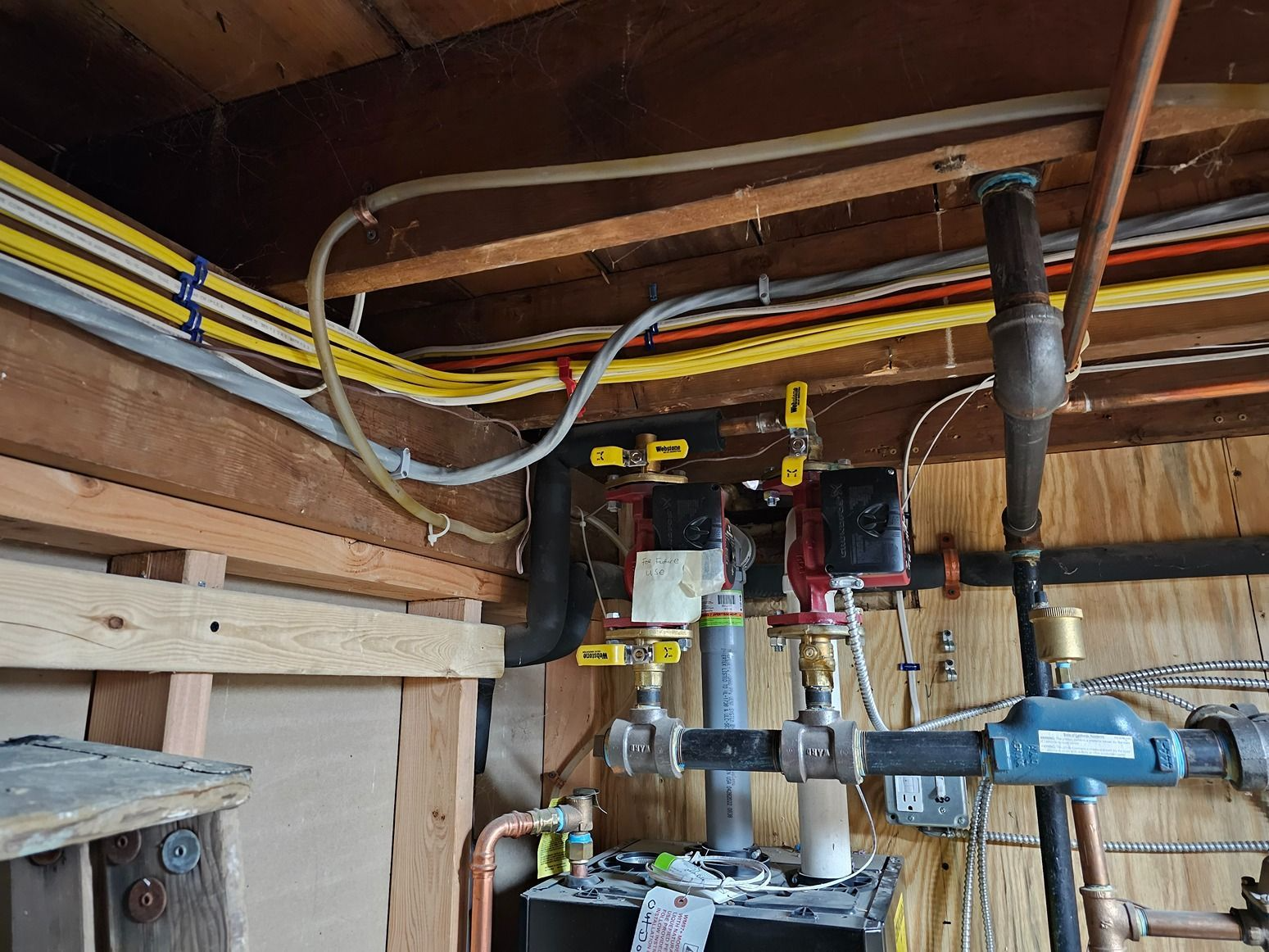 Basement utility area with exposed pipes, valves, and water meters mounted on wood framing.
