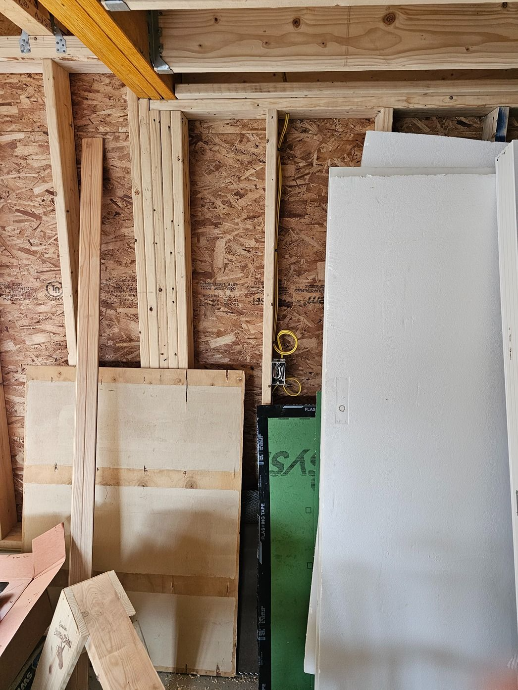 Partially framed workshop wall with insulation boards and lumber stacked inside