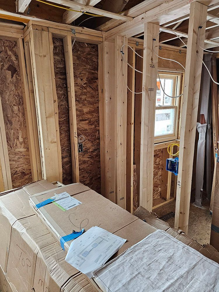Unfinished house interior with exposed wooden framing, insulation, and a window in the wall.