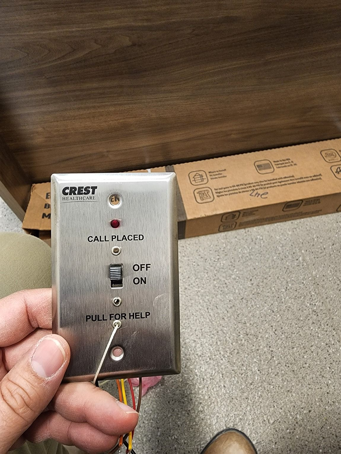 Hand holding a small wired control box labeled CALL IS CANCEL with ON/OFF and MULTI-CALL options