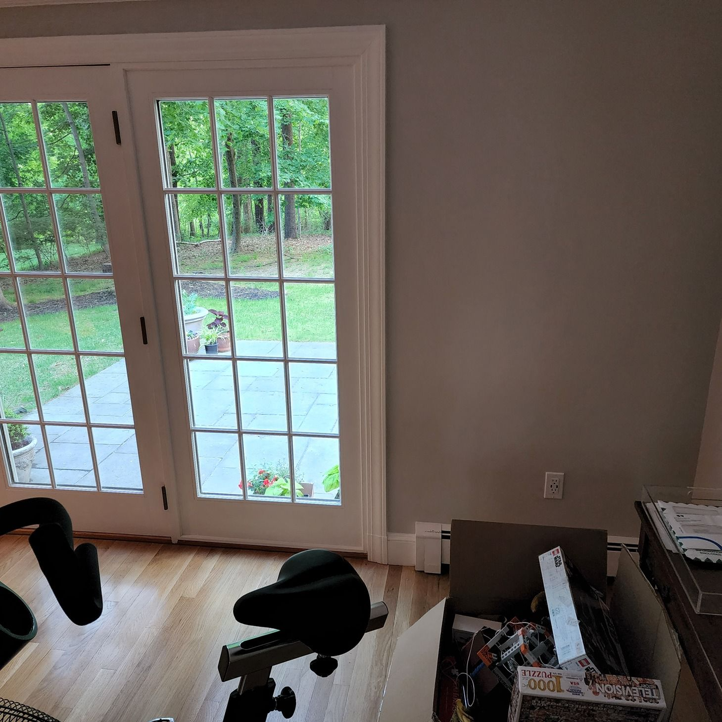 Living room with French doors, hardwood floor, exercise bike, and moving boxes by the wall