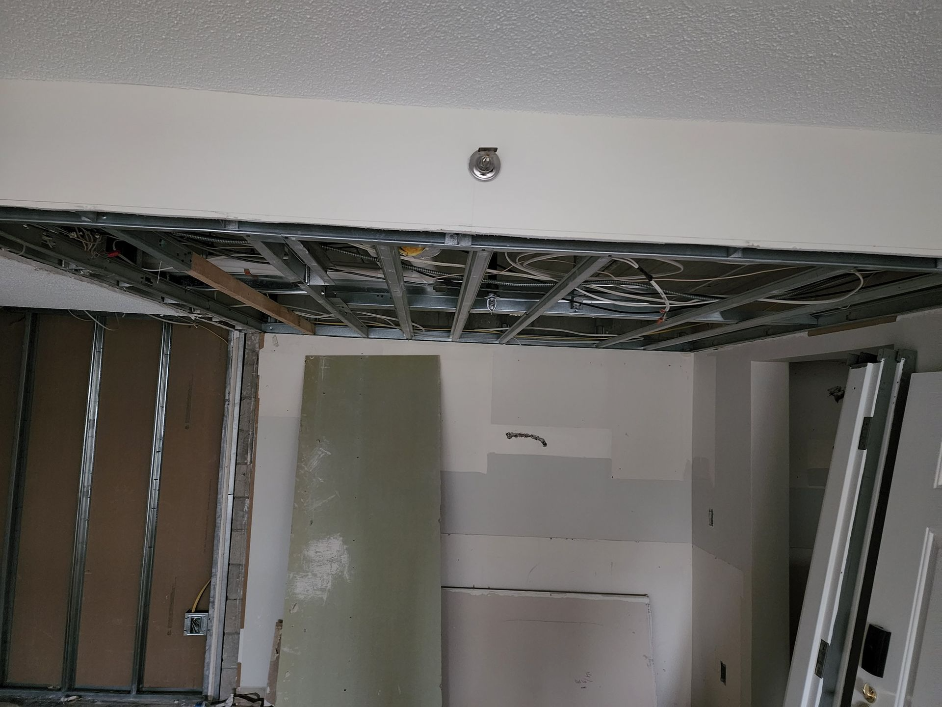 Interior room with exposed ceiling joists, unfinished drywall, and construction debris
